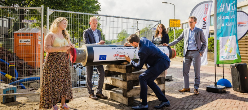 Foto van wethouder Kraaijeveld die zijn handtekening zet op een warmtenetleiding